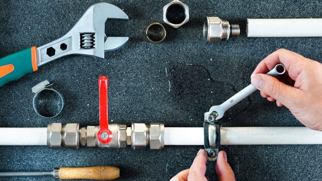 Plumber repairing a pipe valve with an adjustable wrench in The Villages