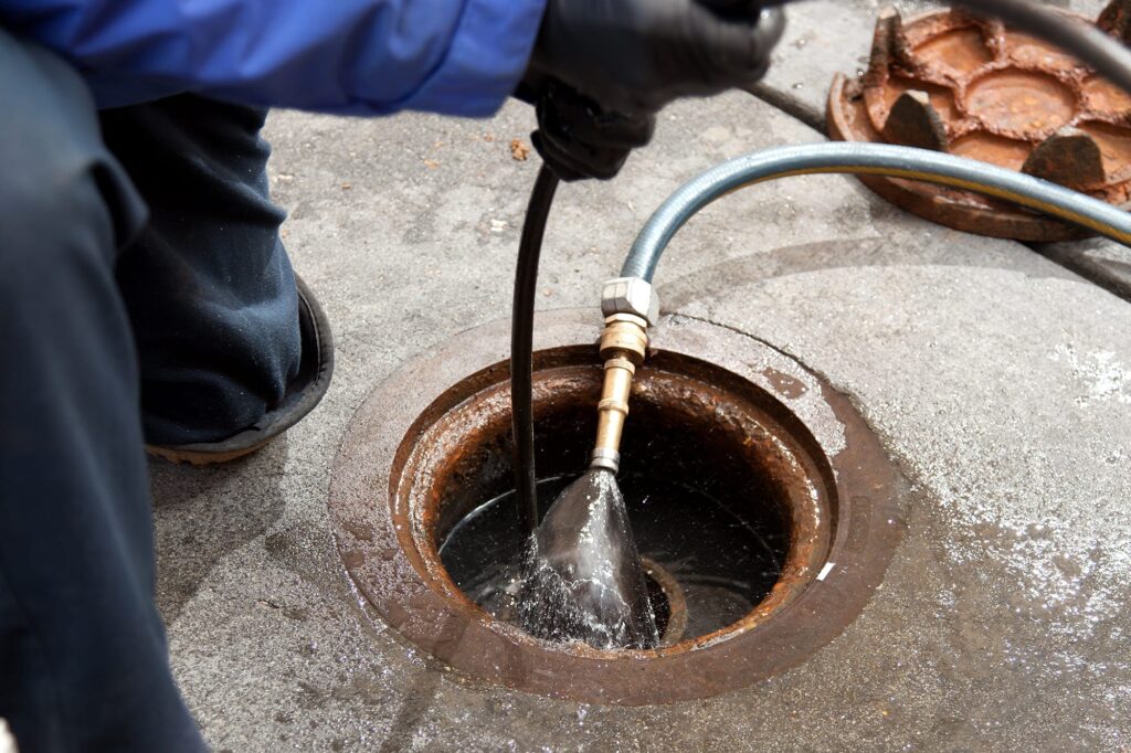 Plumber hydro jetting a sewer line through a manhole in The Villages